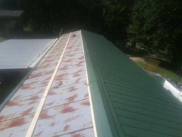 Old rusted panels beside newly installed green metal roofing — Wind Damage Roof Repair by Roofing Brothers in Leonardtown