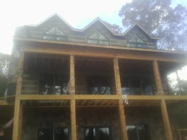 Dormers and porch framing on a large log home under construction — Roof Coating work by our crew in Leonardtown