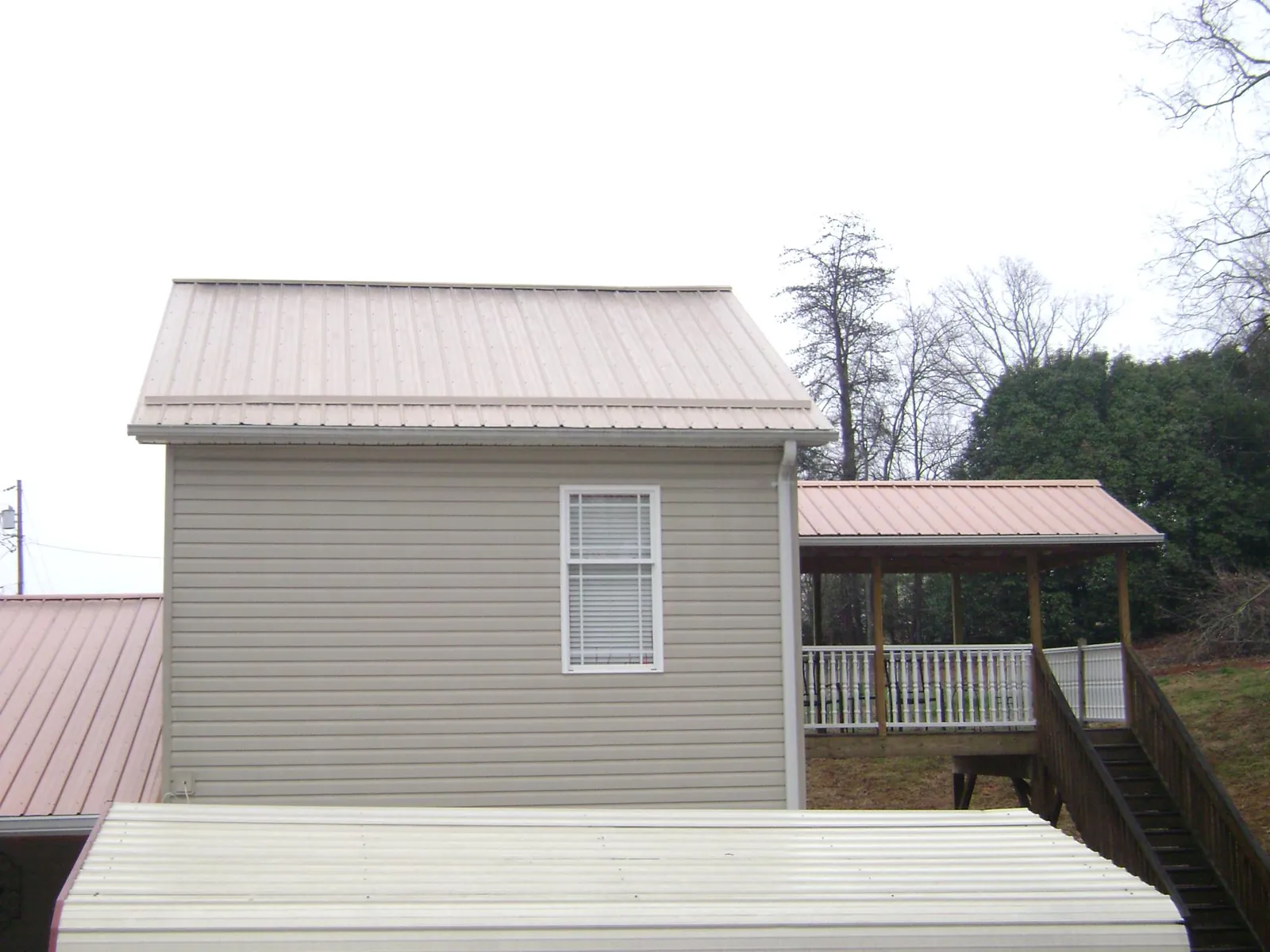 Tan metal roofs on a two story addition and attached porch, from a Roof Replacement job in Leonardtown