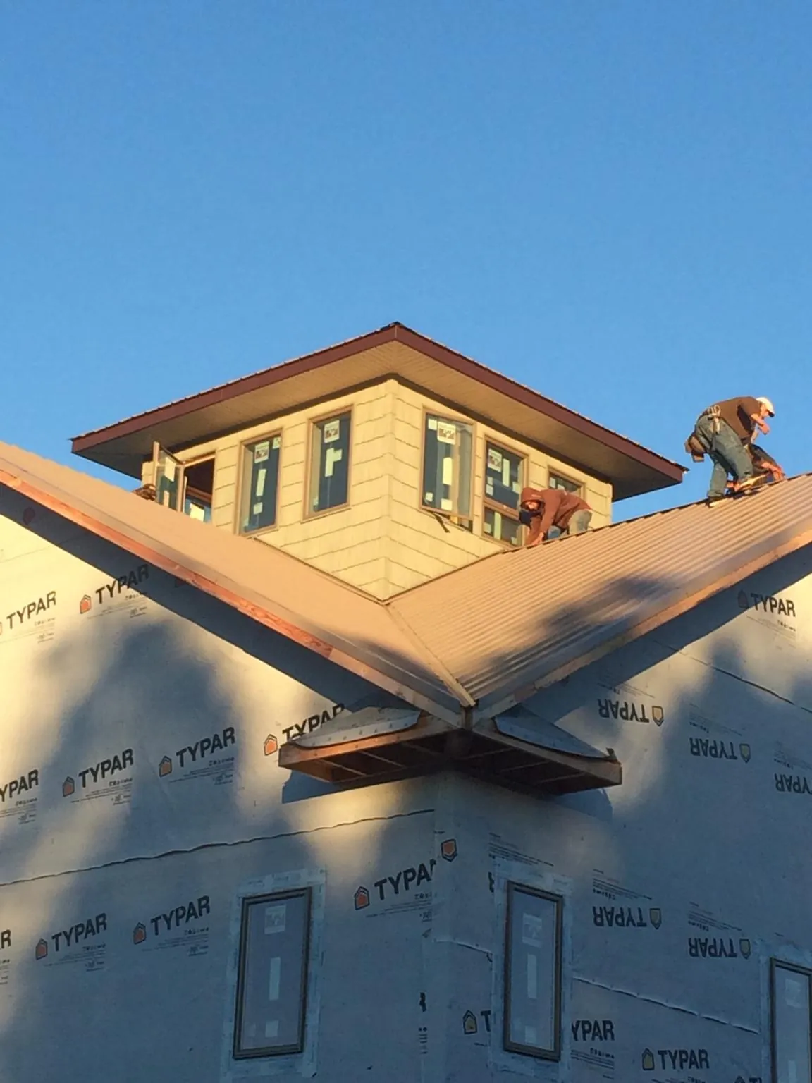 Roofers working around a rooftop cupola on a new metal roof at sunset — Roof Waterproofing in Leonardtown by Roofing Brothers